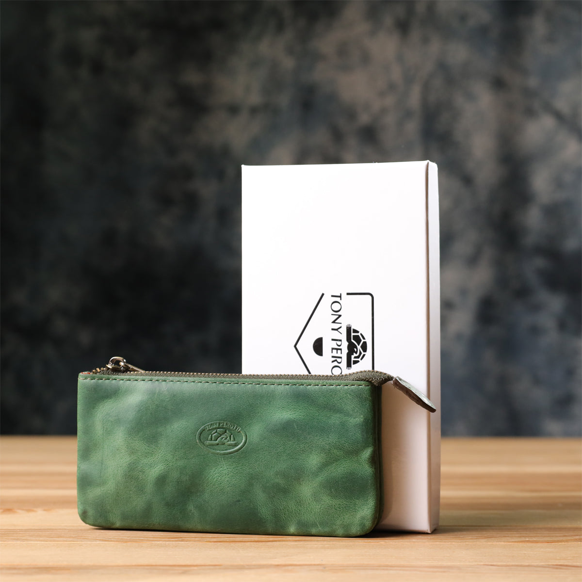 Back of the Tony Perotti Arno 3350 deep green key case standing on a wooden surface against a dark textured background