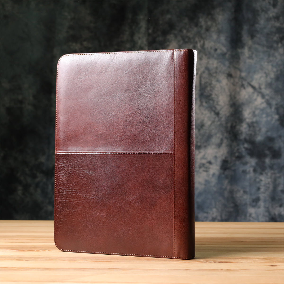 Back of the dark brown Italico 1278L leather padfolio standing on a wooden desk — smooth glossy bull leather with contrasting stitching