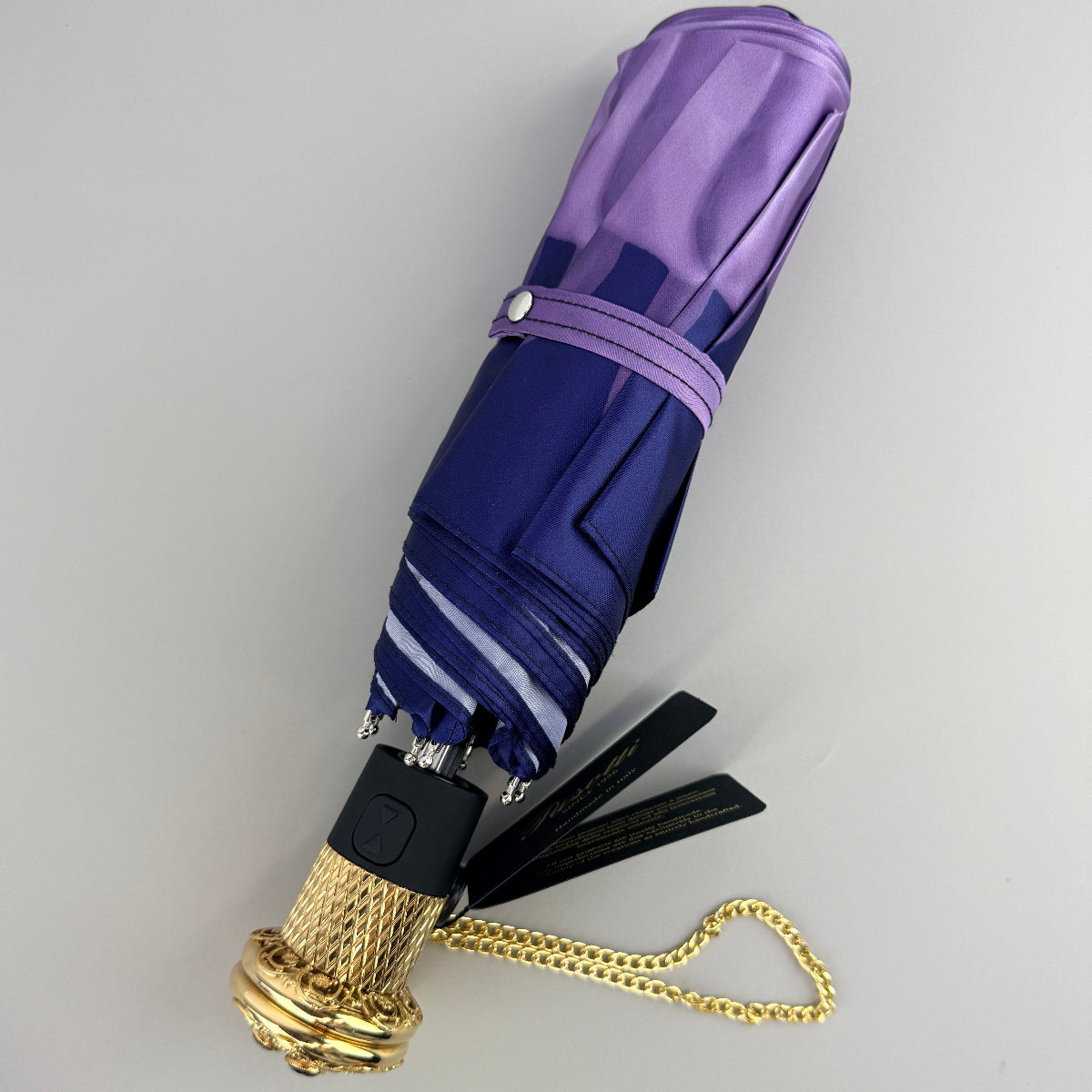 Pasotti purple and gold umbrella on a light gray background