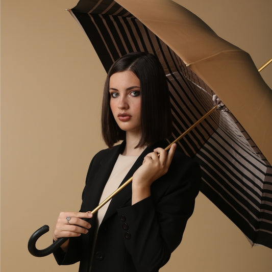 Woman holding a striped umbrella against a beige background