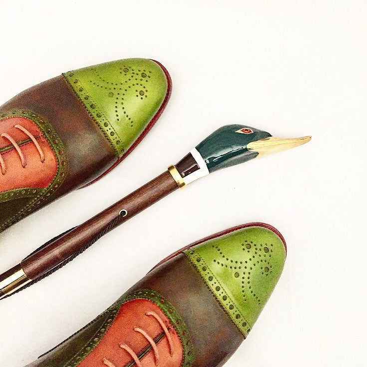 Mallard shoehorn lying between a pair of green and brown brogues