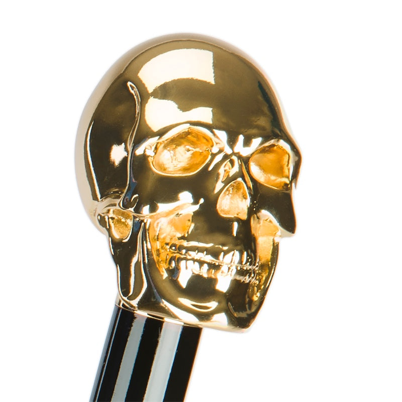 Gold-tone skull handle in three-quarter view on a glossy black grip