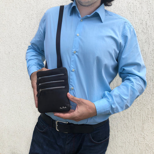 Man in a light blue shirt holding the Tony Perotti Contatto 9019 crossbody bag worn across the chest