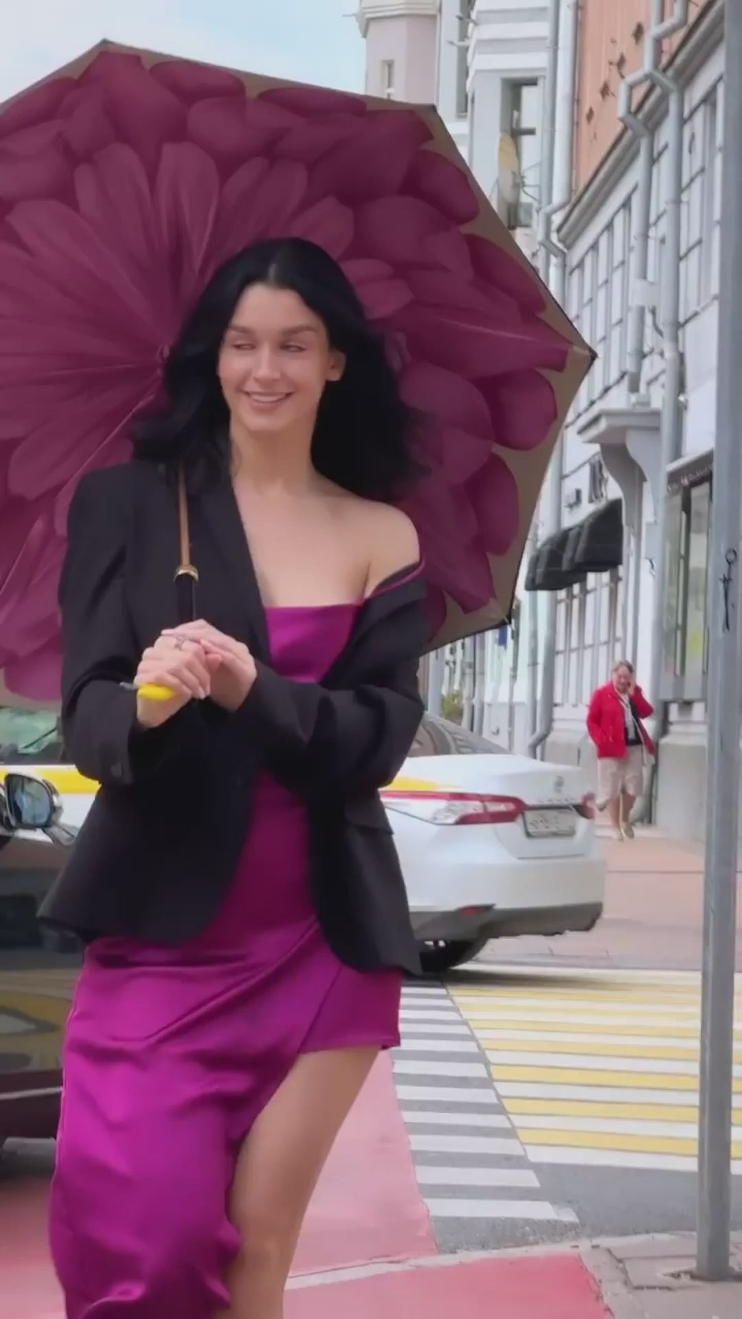 A girl with a Flamingo umbrella walks down a city street