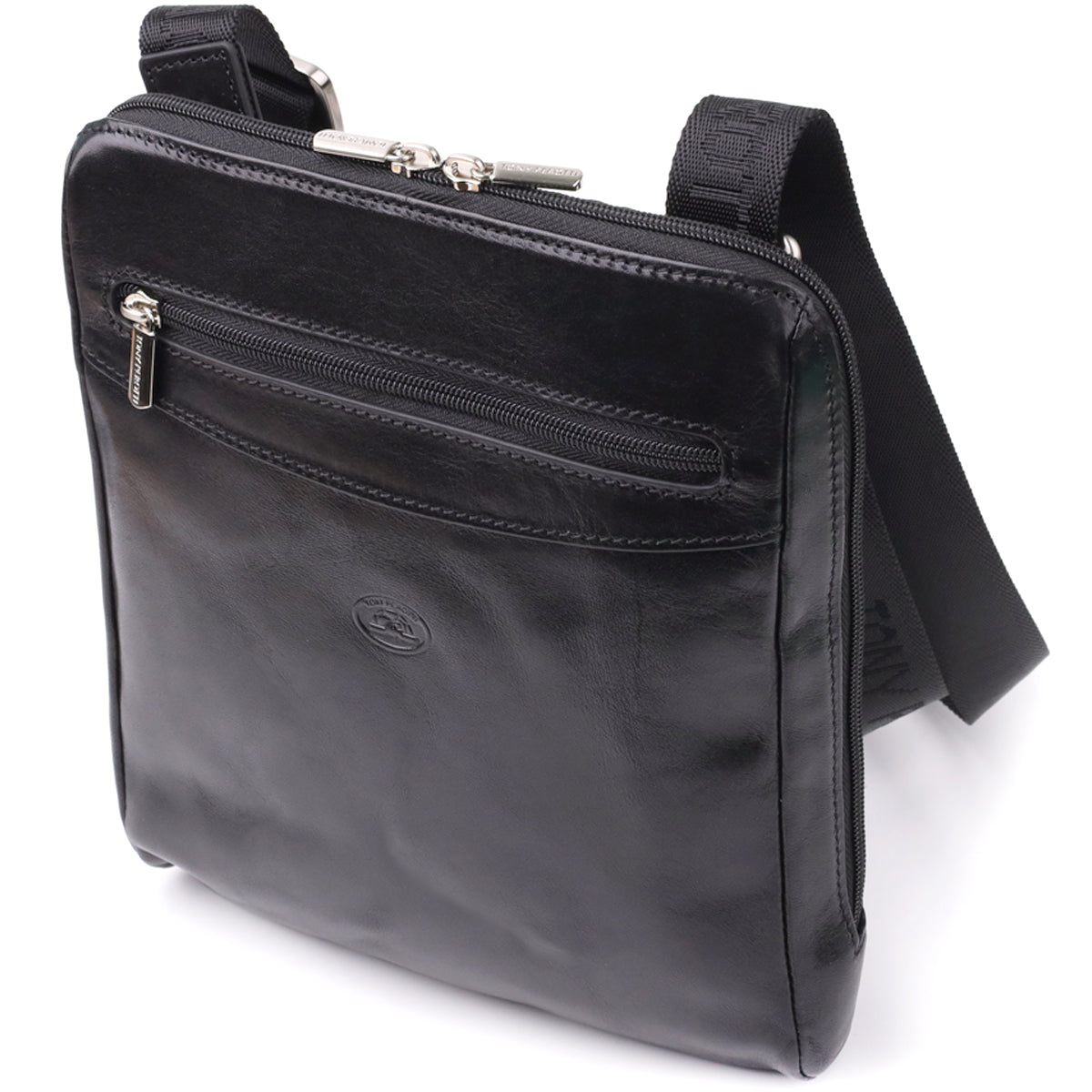Three-quarter angled view of the Tony Perotti Italico 9137-20 black leather crossbody bag showing the front zip pocket, embossed oval emblem and adjustable jacquard shoulder strap