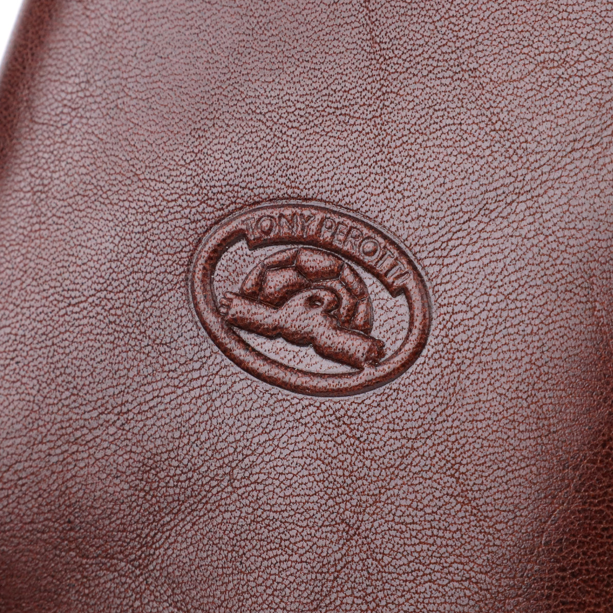 Macro close-up of the embossed oval Tony Perotti emblem on the Italico 1438 moro wallet, showing the turtle design clearly