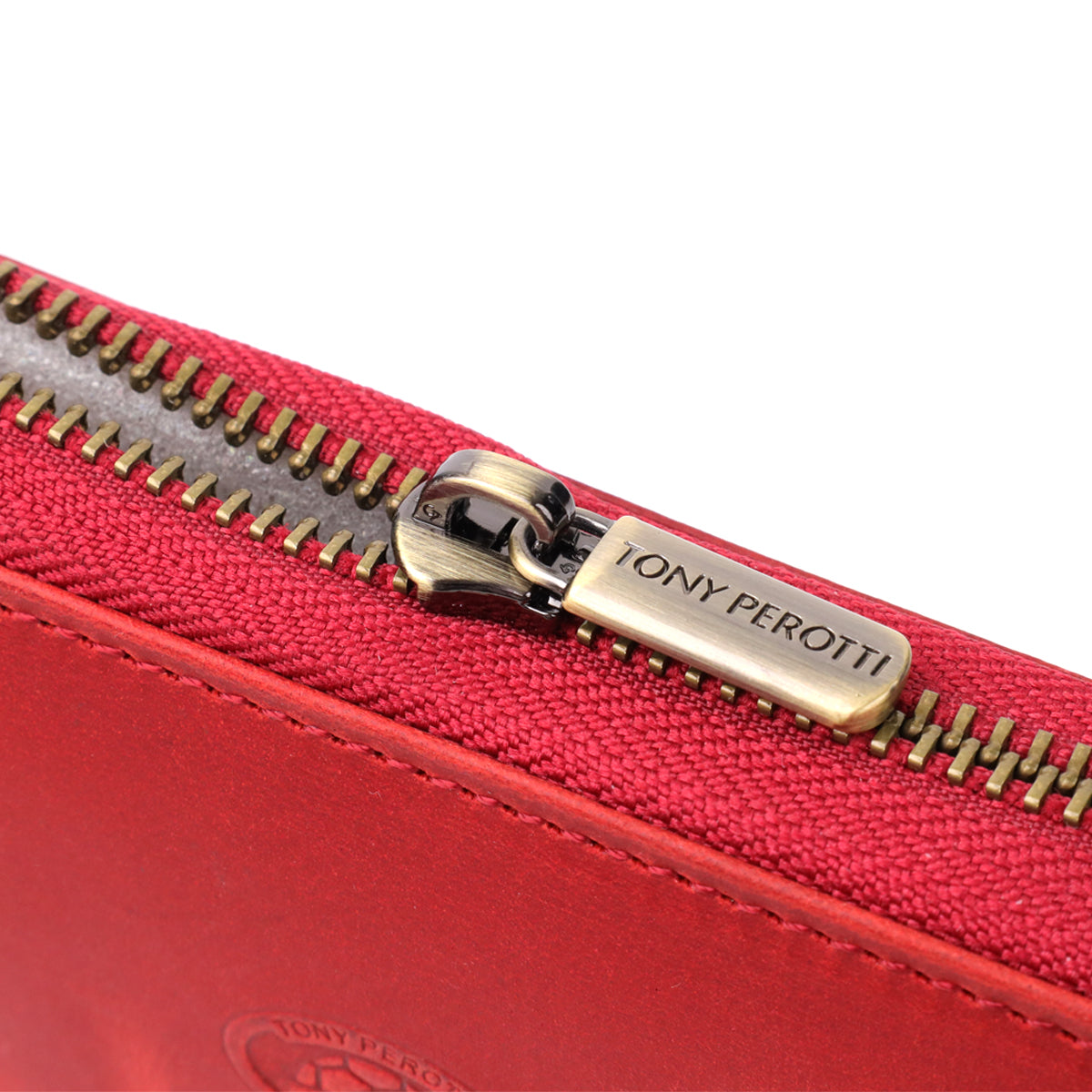 Macro close-up of the zip pull on the Tony Perotti Arno 2250 rosso wallet, stamped Tony Perotti