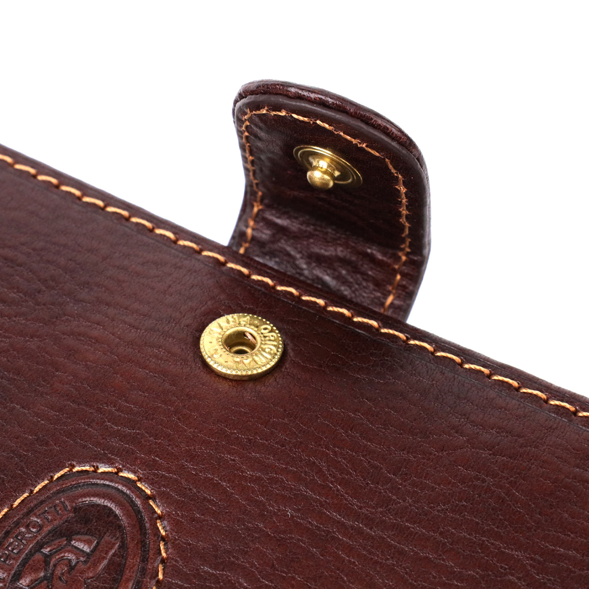 Macro close-up of the snap-tab closure on the Tony Perotti Italico 1423A moro document holder, showing the embossed leather logo patch beside it