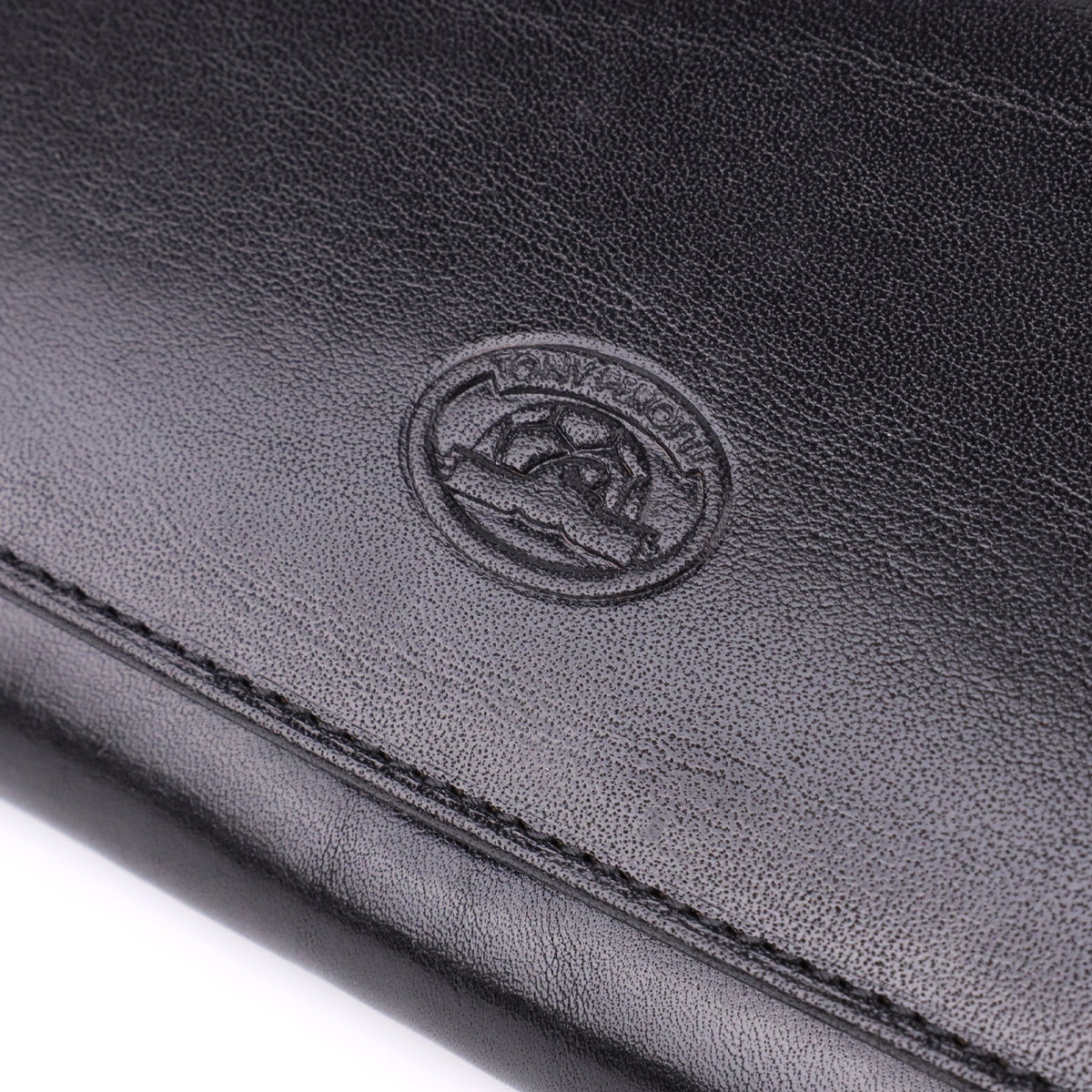 Macro close-up of the embossed oval Tony Perotti emblem on the Italico 1073 nero wallet, showing the turtle design clearly