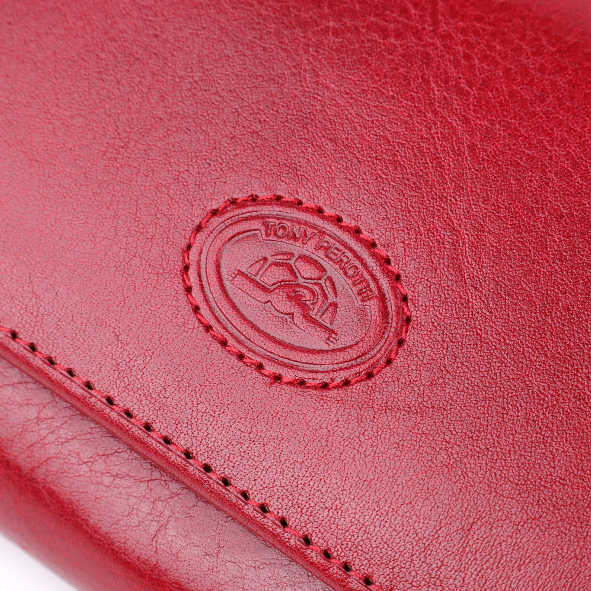 Macro close-up of the embossed oval Tony Perotti emblem on the Italico 1911 rosso wallet, showing the turtle design clearly