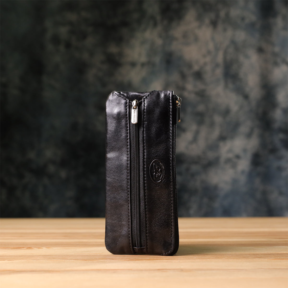 Tony Perotti Italico 2686 nero black leather key case standing upright on a wooden surface against a dark textured background