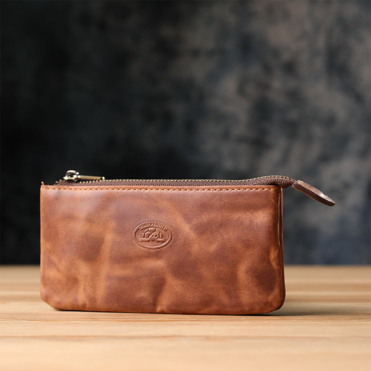 Tony Perotti Arno 3350 whisky leather key case standing on a wooden surface against a dark textured background