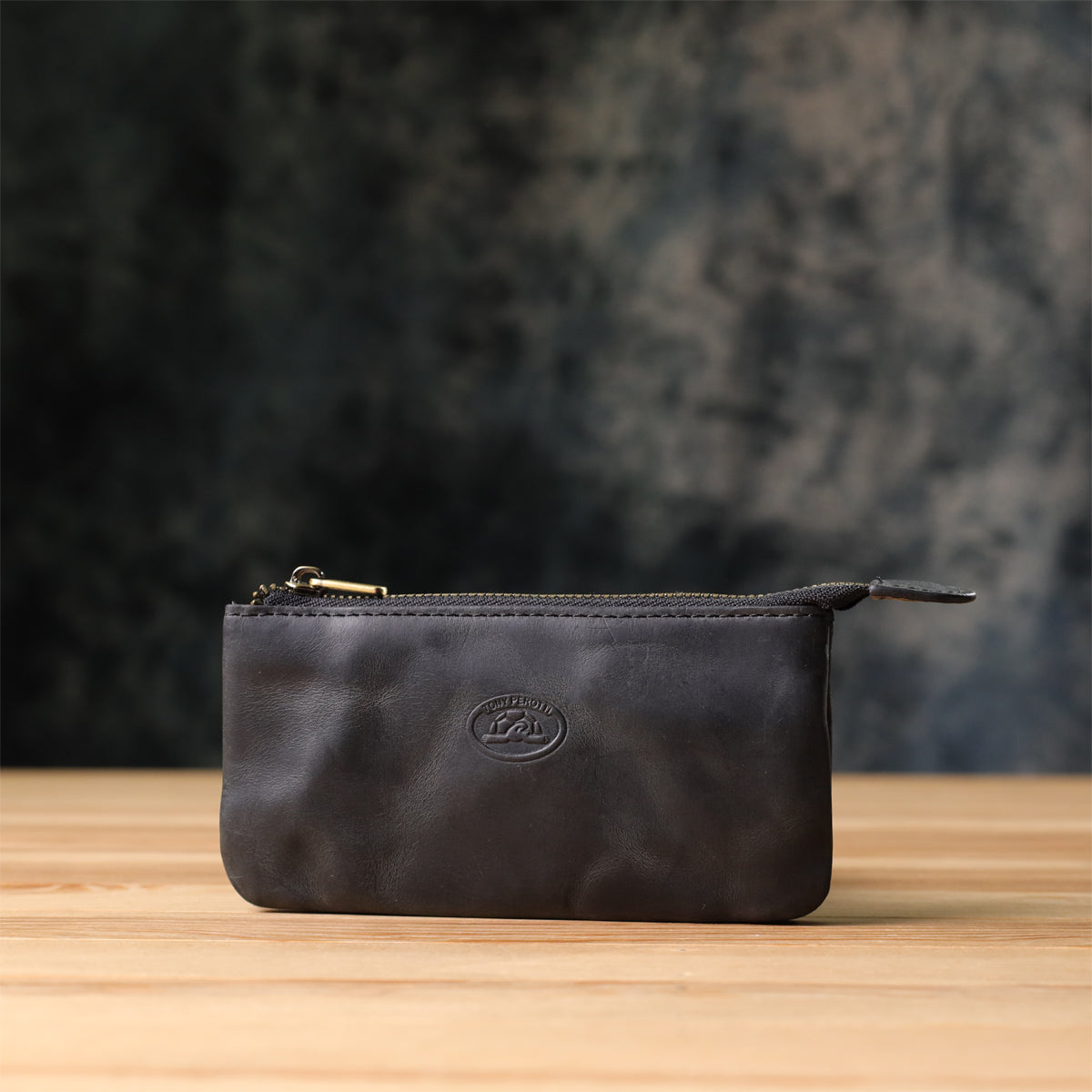 Tony Perotti Arno 3350 nero leather key case standing on a wooden surface against a dark textured background