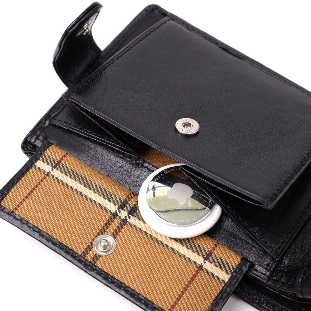 Macro close-up of the snap coin pocket on the Tony Perotti Italico 396A-Q nero wallet — tartan lining inside, shown holding an Apple AirTag