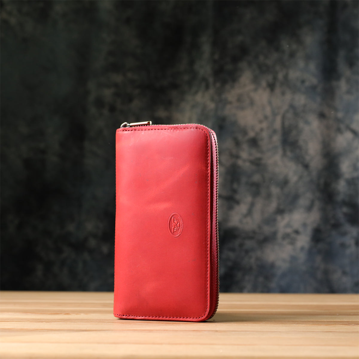 Tony Perotti Arno 2250 rosso red leather wallet standing on a wooden surface against a dark textured background