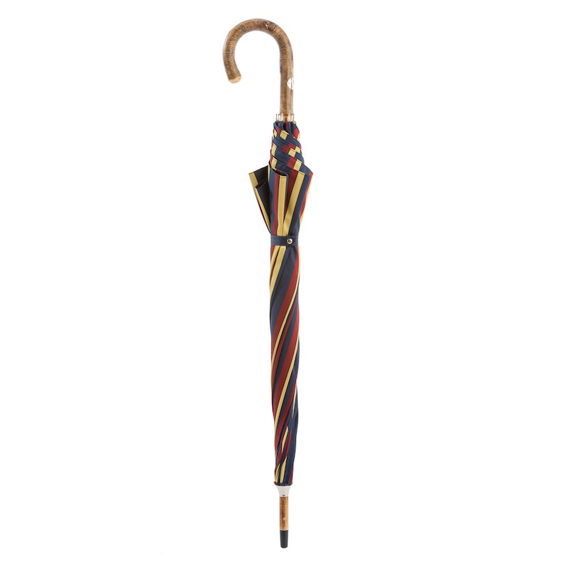 Closed navy, burgundy and mustard striped umbrella standing upright with ash crook handle