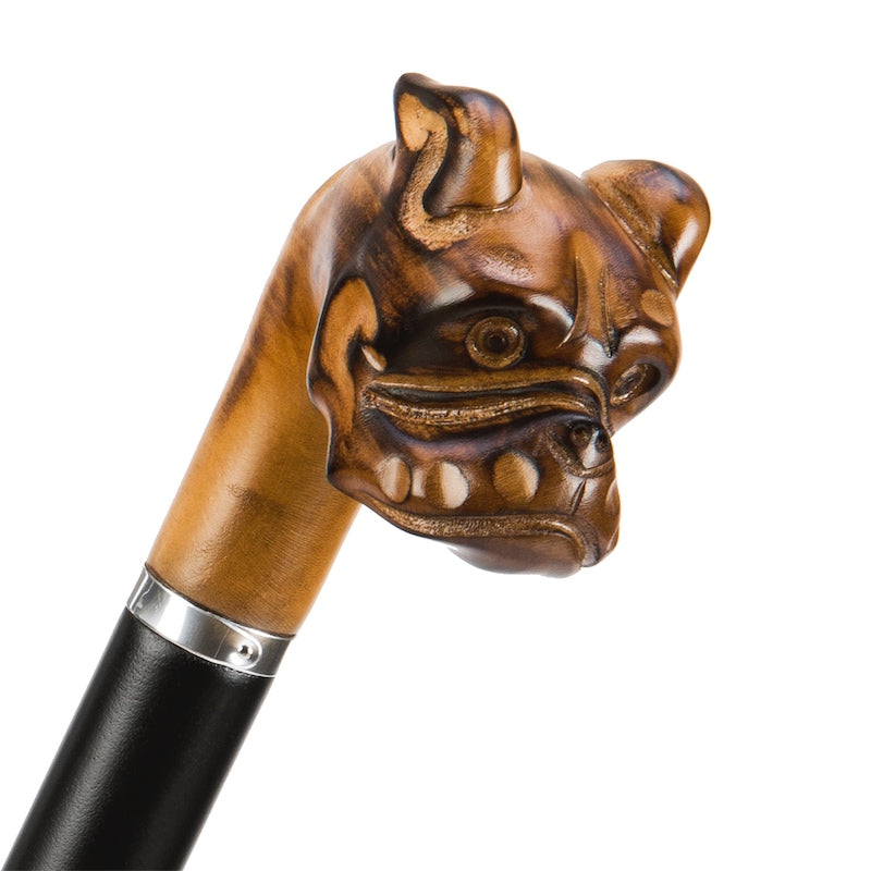 Hand-carved wooden bulldog head handle with silver-tone ring above the black grip, close-up, handcrafted in Italy