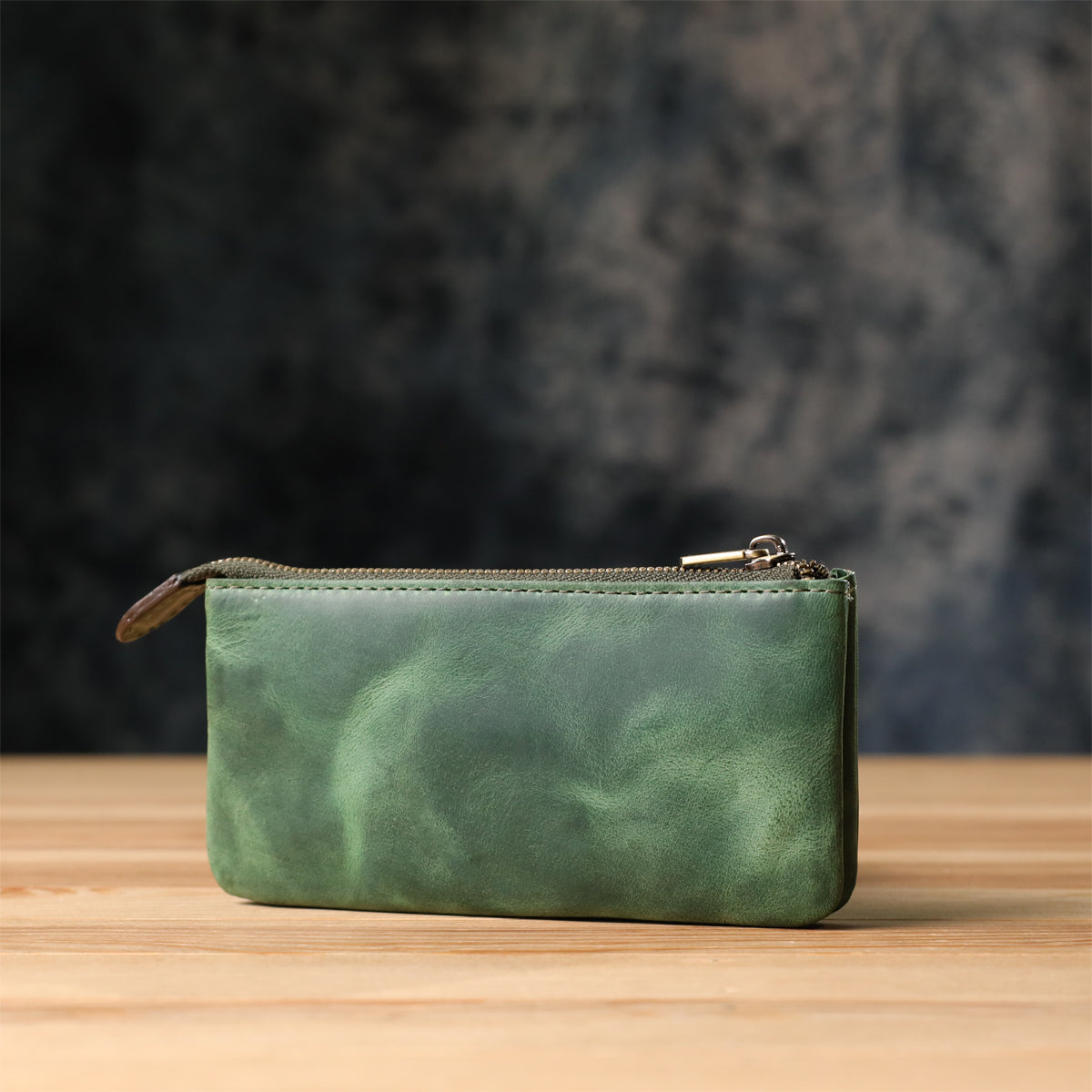 Tony Perotti Arno 3350 deep green leather key case standing on a wooden surface against a dark textured background