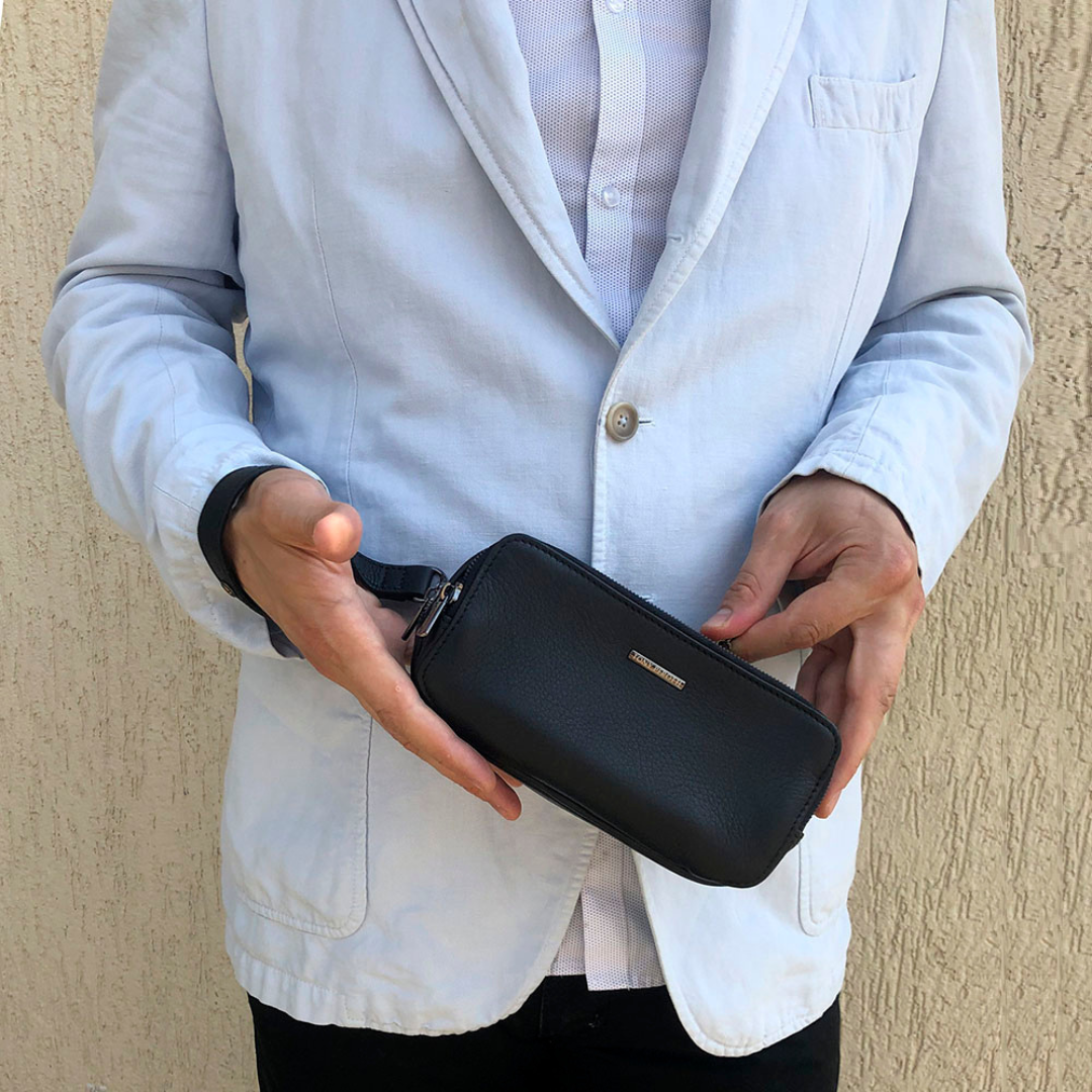 Man in a light blazer holding the black Tony Perotti leather clutch in both hands