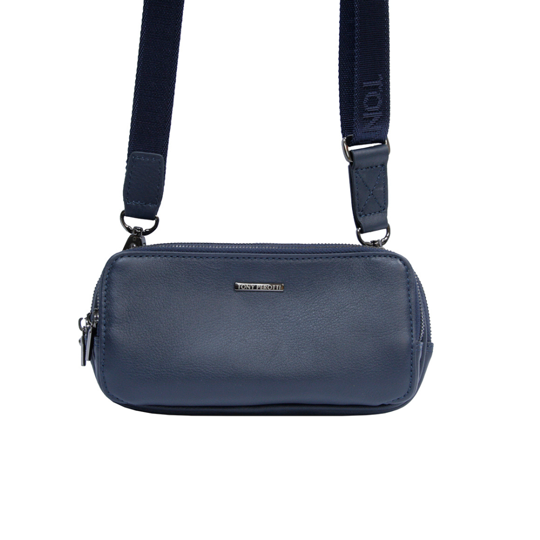 Navy leather clutch worn as a crossbody bag with the textile shoulder strap clipped to both D-rings