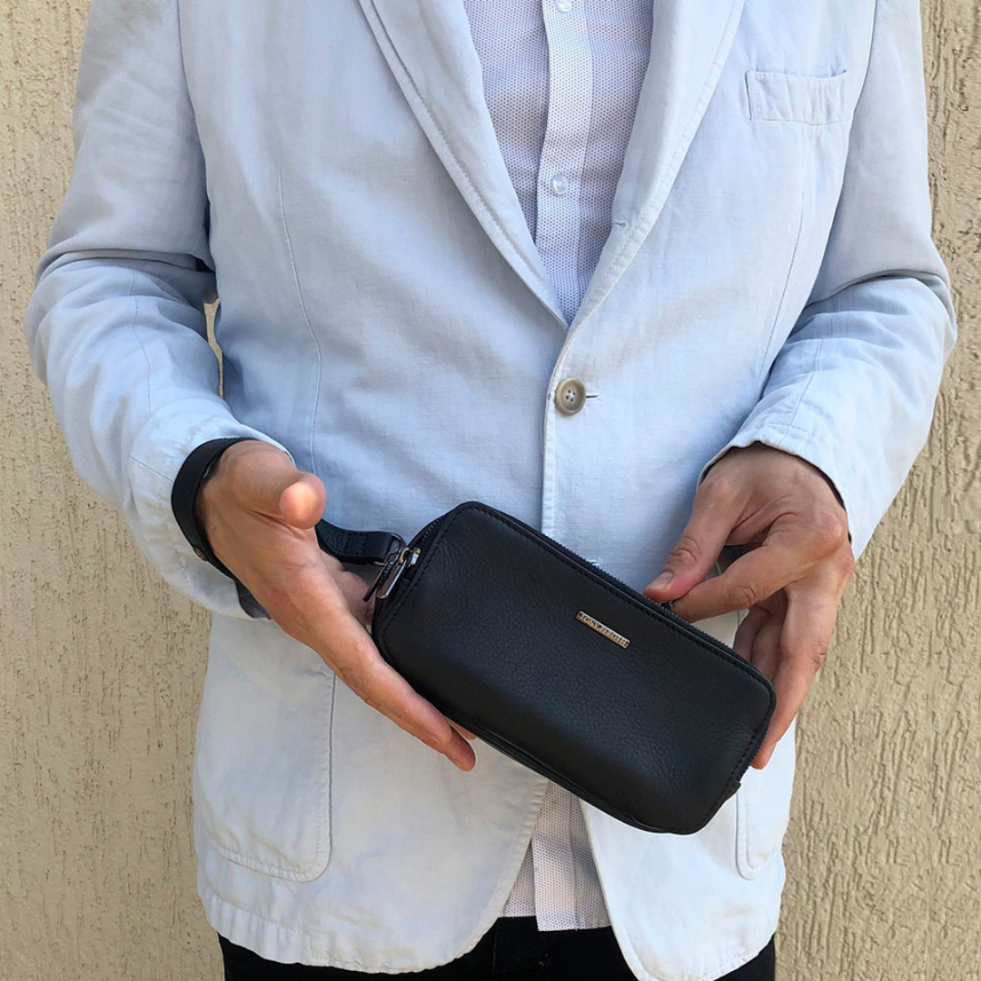 Man in a light blazer holding the Tony Perotti New Contatto 6168 clutch in both hands — the black version is shown