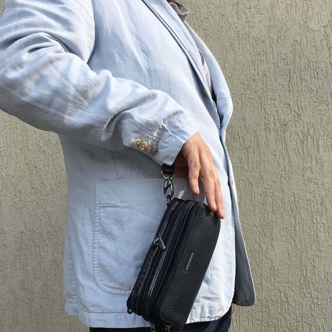 Tony Perotti New Contatto 6168 clutch carried on the wrist strap at the hip — the black version is shown