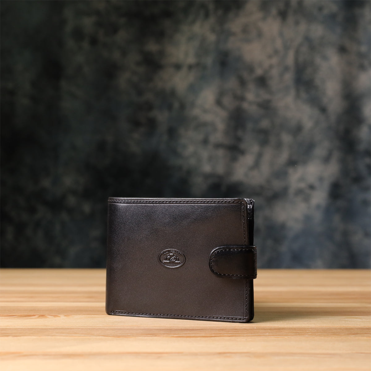 Tony Perotti Italico 396A-Q nero black leather bifold wallet standing on a wooden surface against a dark textured background