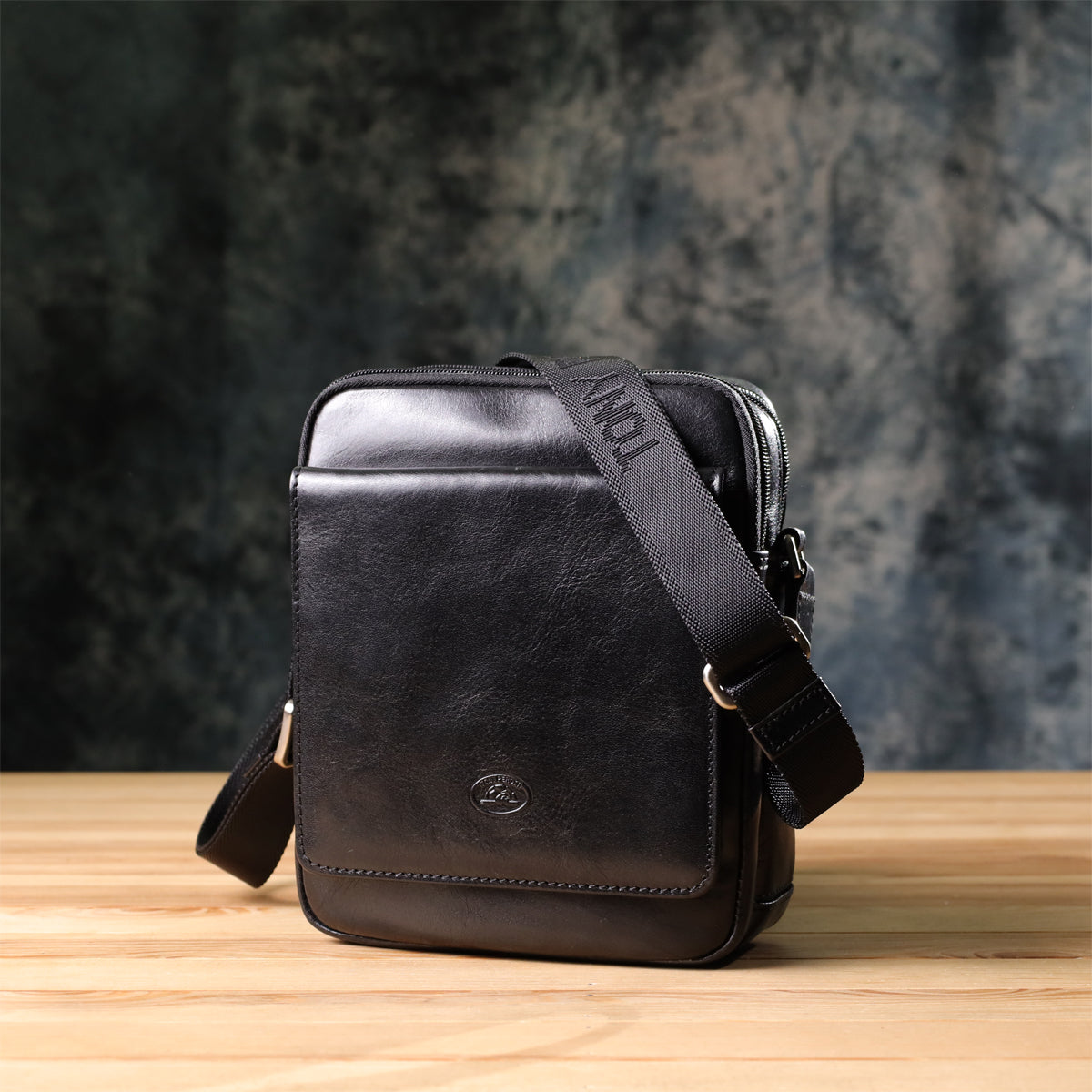 Italico 9148-17 black bag photographed on a wood surface against a dark textured backdrop