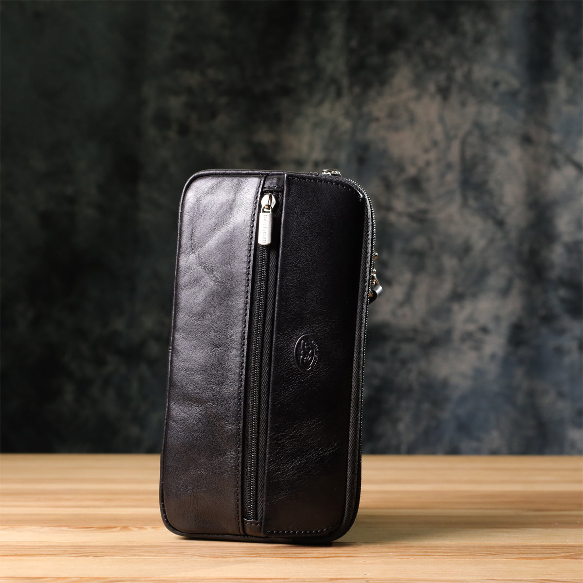 Tony Perotti Italico 9405 nero black leather clutch standing upright, side profile, on a wooden surface against a dark textured background