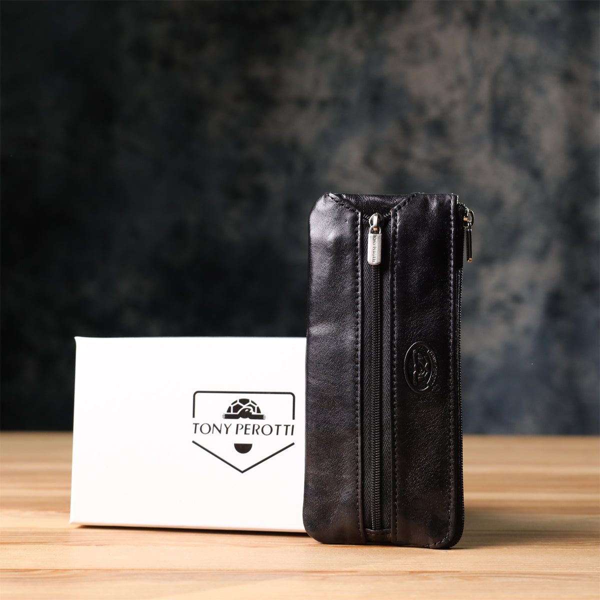 Tony Perotti Italico 2686 nero black leather key case standing next to its small white Tony Perotti gift box on a wooden surface