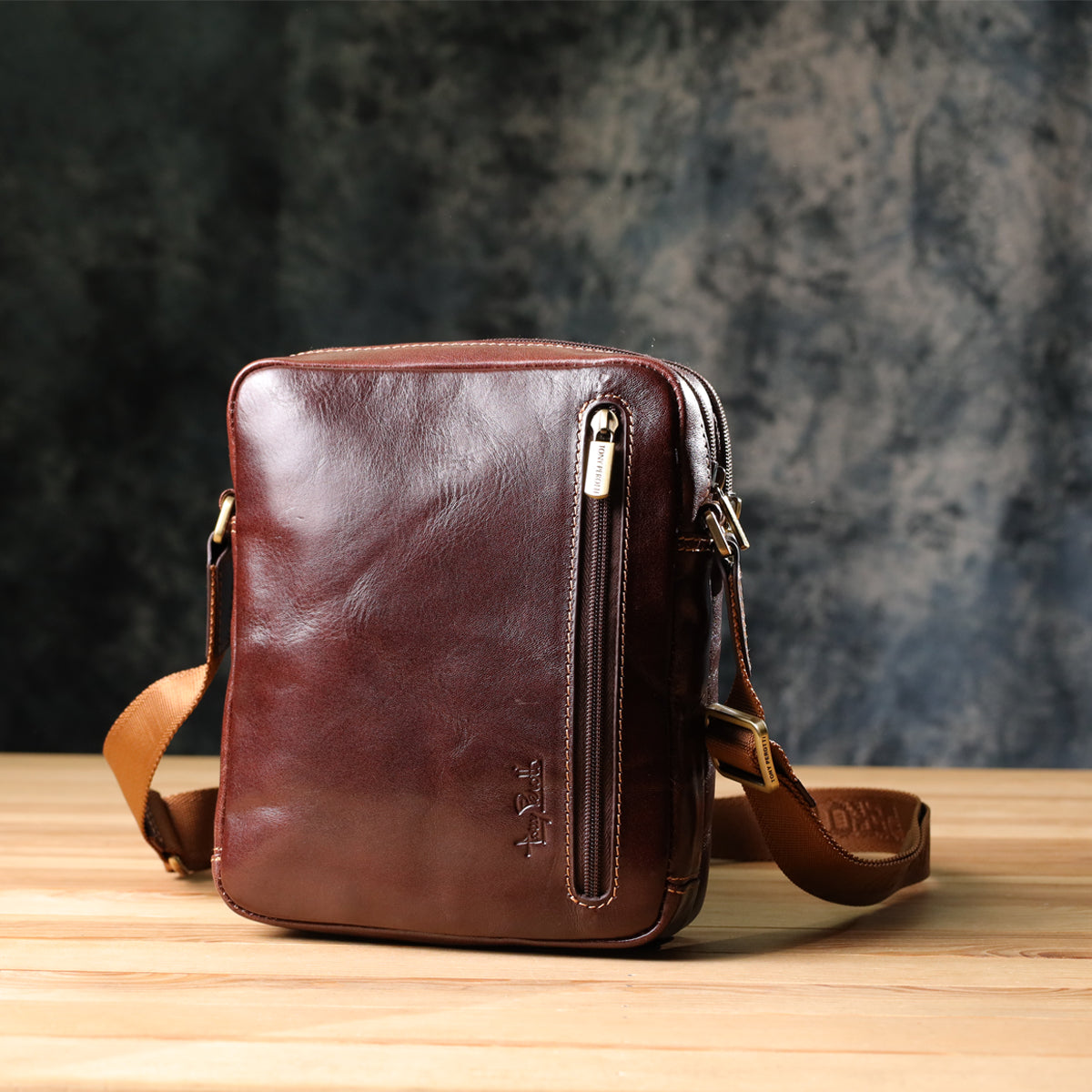 Side angled view of the Italico 9148-17 bag on a wood surface, showing the front zip pocket and strap buckle