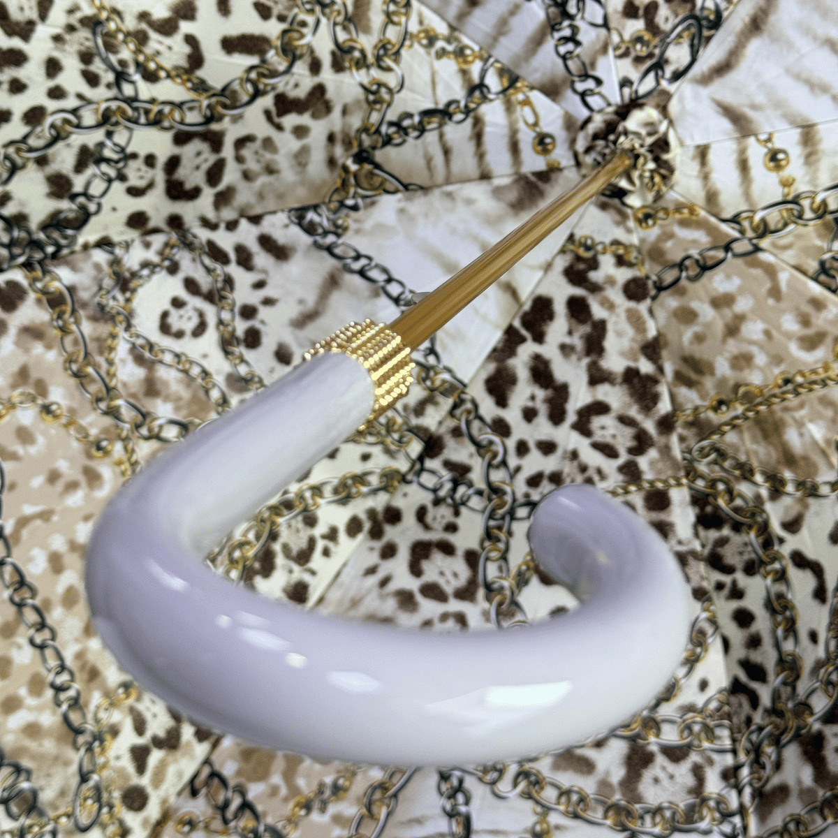 Glossy grey plastic crook handle against the leopard-print inner canopy — Pasotti 189-58002/9-2