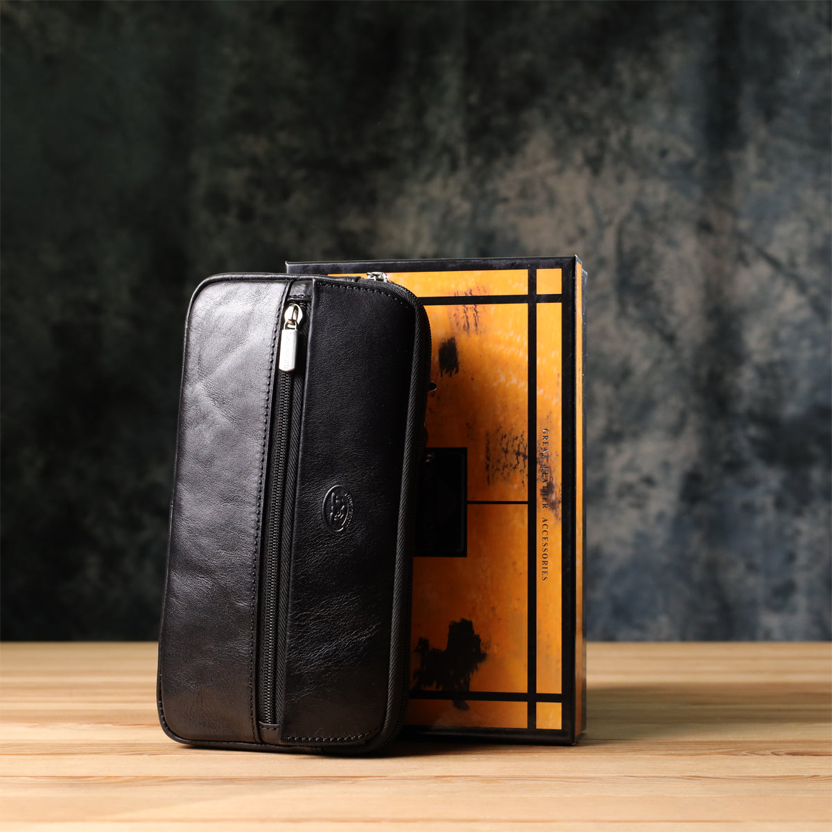 Tony Perotti Italico 9405 nero black leather clutch standing next to its branded gift box on a wooden surface