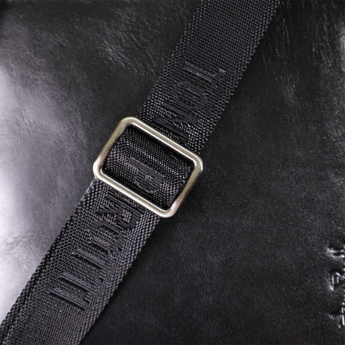 Macro shot of the strap's metal slide buckle on the Italico 9137-20 bag with TONY PEROTTI woven into the webbing