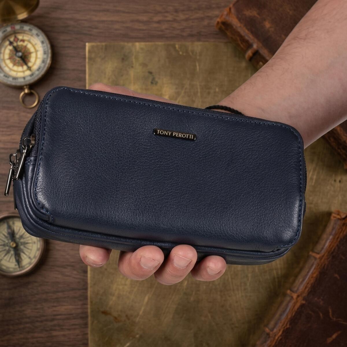 Navy Tony Perotti leather clutch held in one hand — the bag fits comfortably in the palm