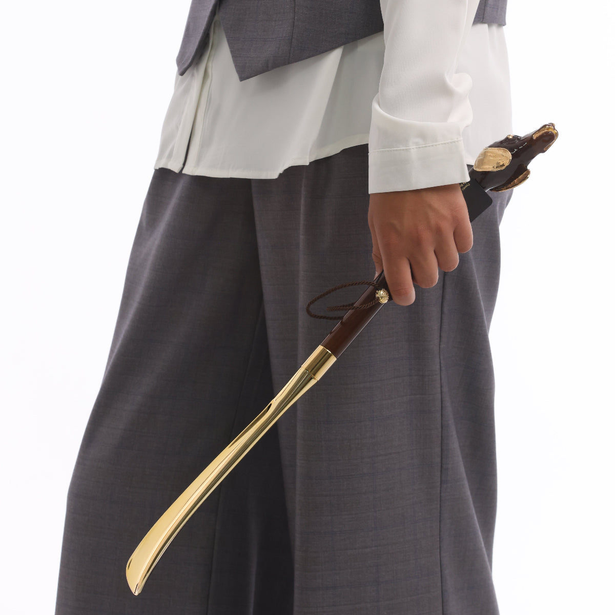 Dachshund head shoehorn held by the wooden shaft, gold-tone blade pointing down