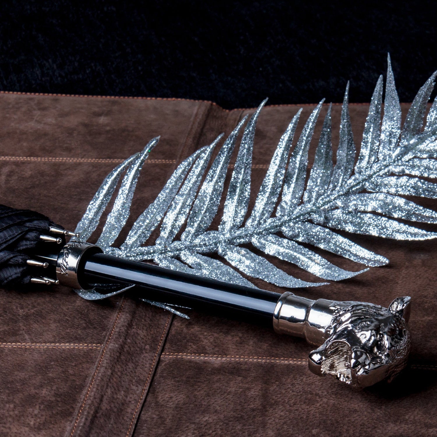 Pasotti cane umbrella with a Silver Tiger handle next to a silver decorative leaf