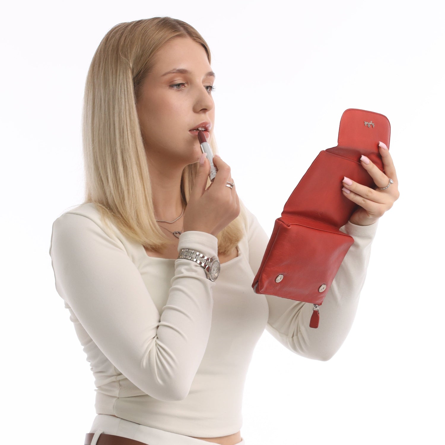 Woman using the built-in mirror in a Tony Perotti red leather cosmetic bag