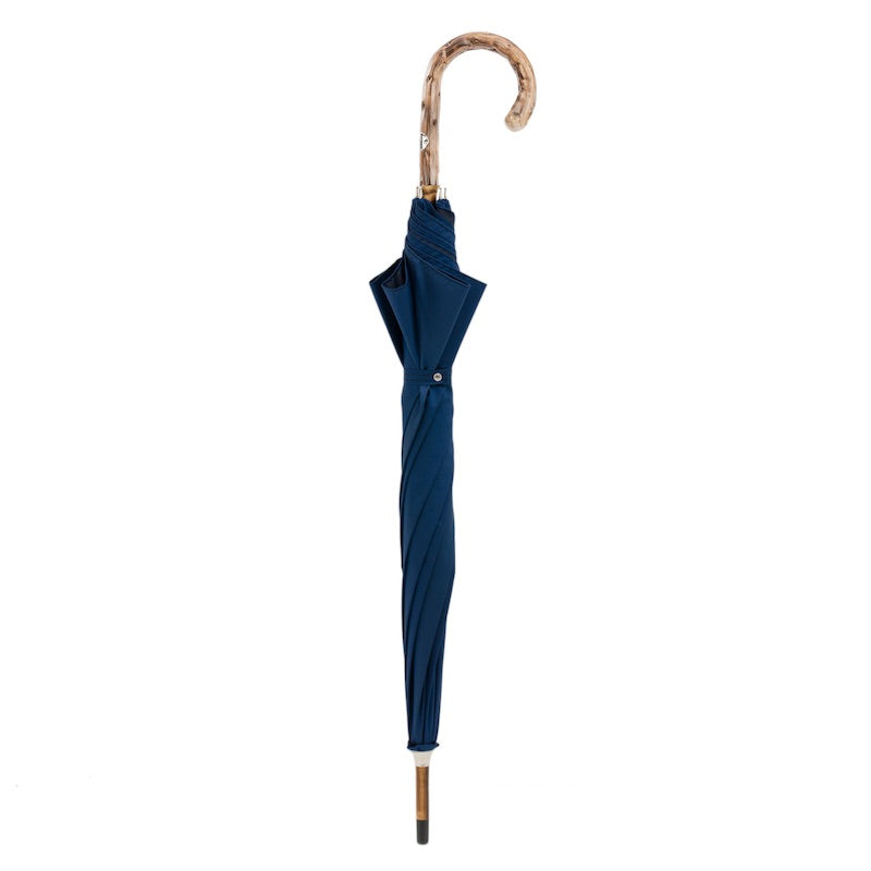 Closed navy umbrella standing upright with gorse wood crook handle
