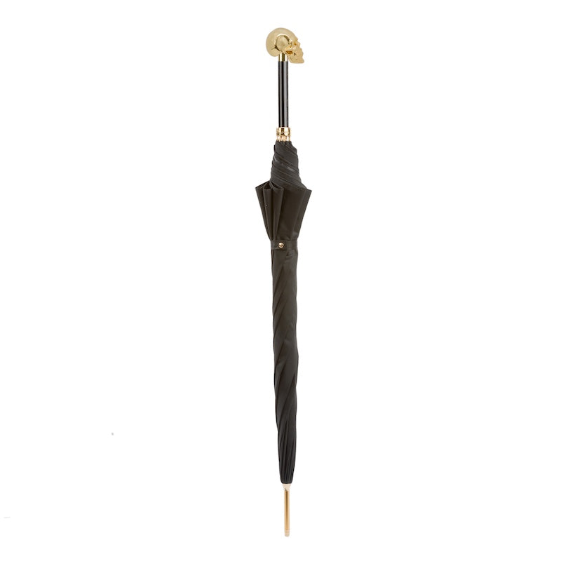 Closed black umbrella standing upright with the gold-tone skull handle and gold-tone tip