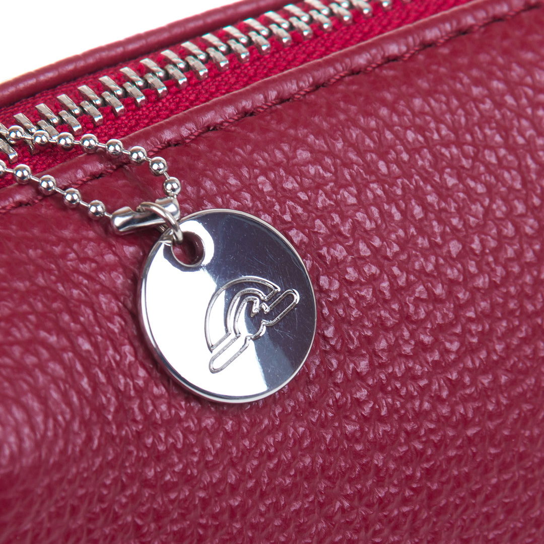 Close-up of the ball-chain zip pull with a round Tony Perotti disc charm on the red pebbled leather