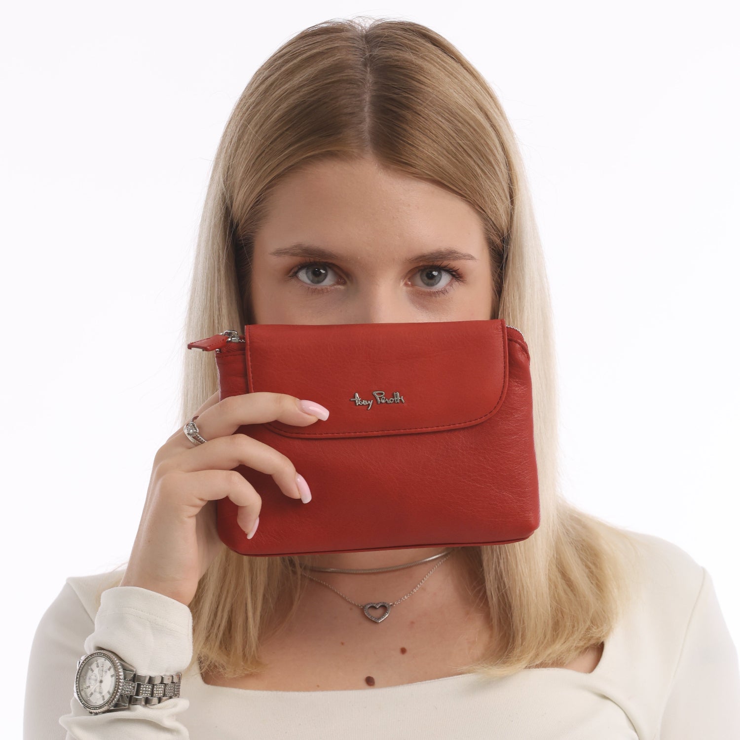 Woman holding Tony Perotti Contatto 2027 rosso red leather cosmetic bag in front of her