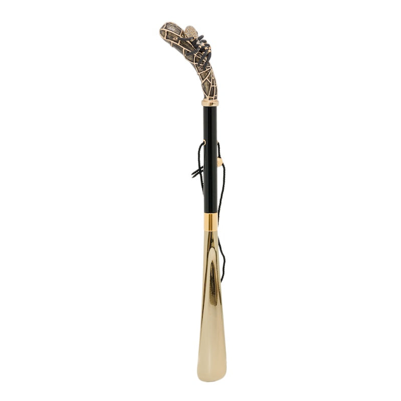 Spider shoehorn standing upright: curved web-pattern handle, glossy black shaft, cord and gold-tone blade