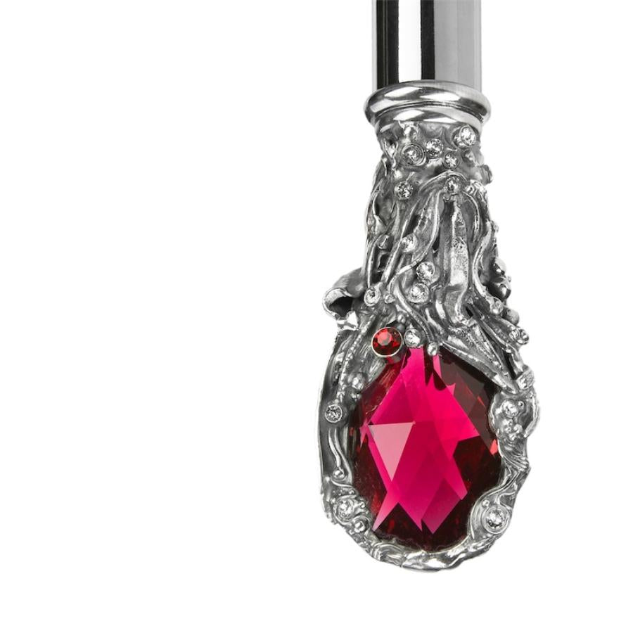 Ornate silver-tone setting with small clear crystals around the red crystal, macro close-up, handcrafted in Italy