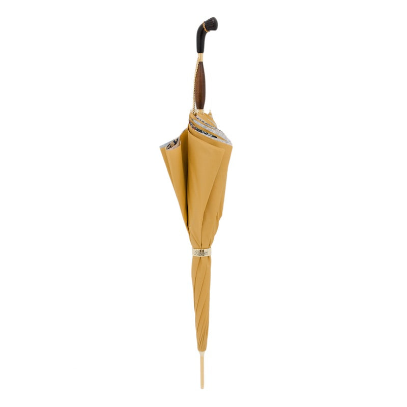 Closed golden yellow umbrella standing upright with the wooden handle and gold-tone ring