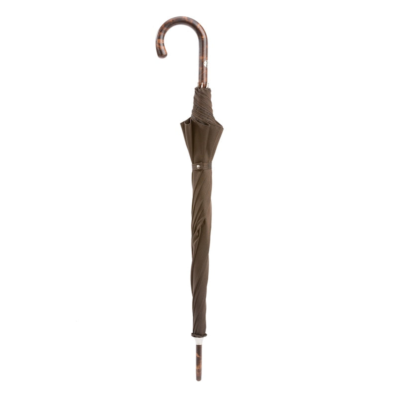 Closed brown umbrella standing upright with hickory crook handle