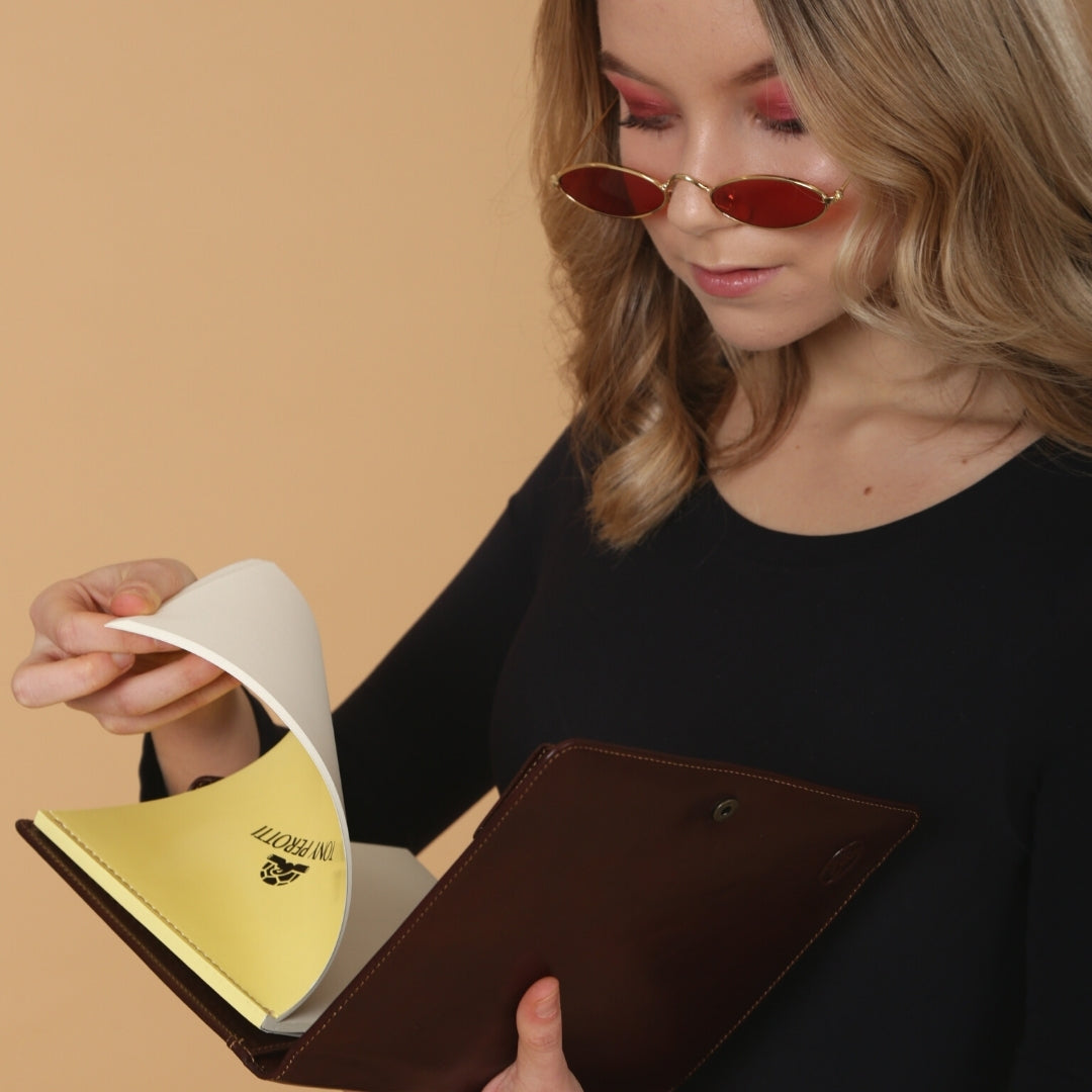 Model turning a sheet of the Tony Perotti notepad inside the open dark brown Italico 2590