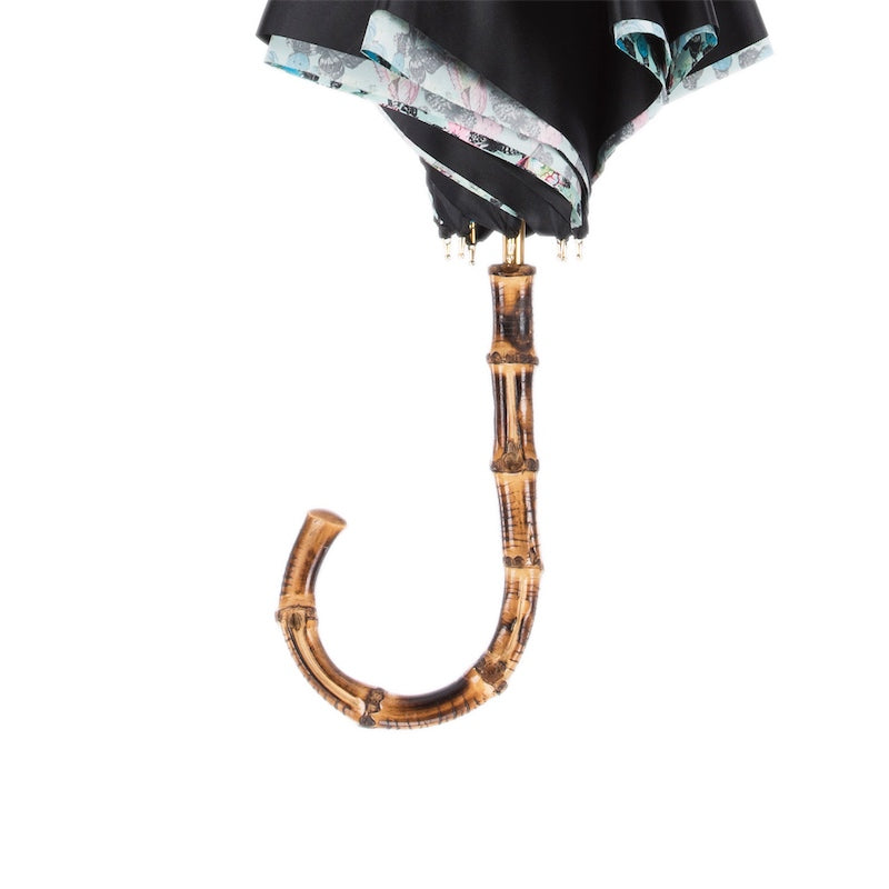 Bamboo crook handle below the furled black canopy with the butterfly print at the edge