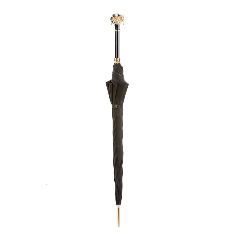 Closed black umbrella standing upright with the jester skull handle and gold-tone tip
