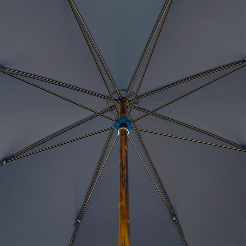 Underside of the open blue canopy with eight ribs and the natural chestnut shaft
